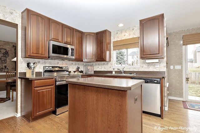 kitchen featuring stainless steel appliances, a kitchen island, light hardwood / wood-style floors, and sink