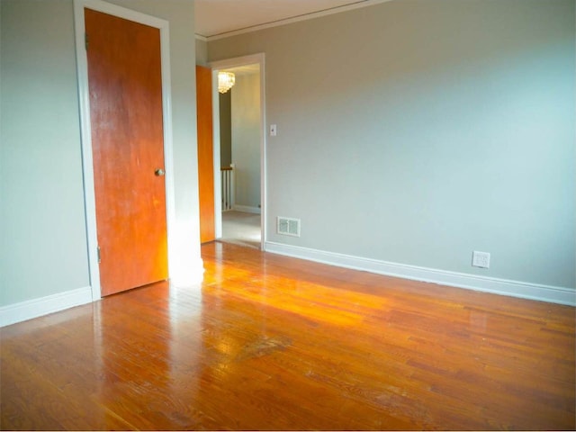 empty room with a chandelier and wood-type flooring