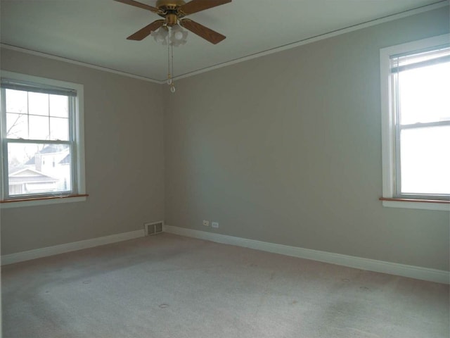 carpeted empty room with crown molding, ceiling fan, and a healthy amount of sunlight