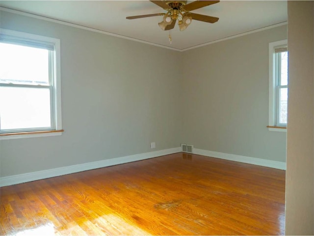 empty room with hardwood / wood-style flooring, ceiling fan, a healthy amount of sunlight, and ornamental molding