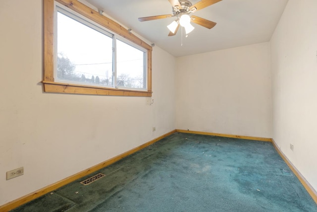 empty room with ceiling fan and dark colored carpet