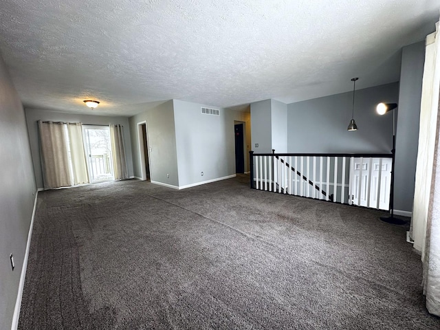 spare room with dark colored carpet and a textured ceiling