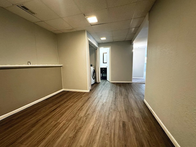 unfurnished room featuring dark hardwood / wood-style flooring, a paneled ceiling, and washer / clothes dryer