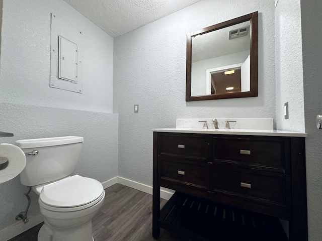 bathroom with vanity, a textured ceiling, hardwood / wood-style flooring, and toilet