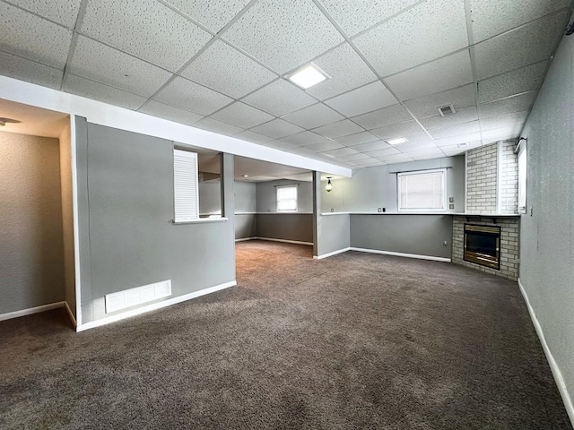 basement with a drop ceiling, carpet floors, and a fireplace