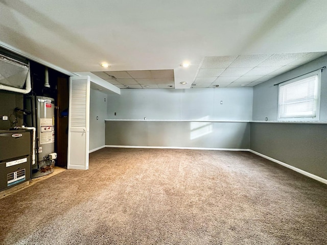 basement featuring a paneled ceiling, carpet floors, and water heater