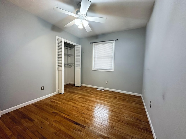 unfurnished bedroom with ceiling fan, a closet, and wood-type flooring