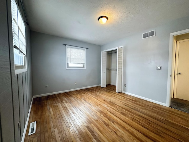 unfurnished bedroom with a closet, a textured ceiling, and light wood-type flooring