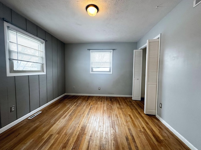 unfurnished bedroom with a textured ceiling and light hardwood / wood-style flooring