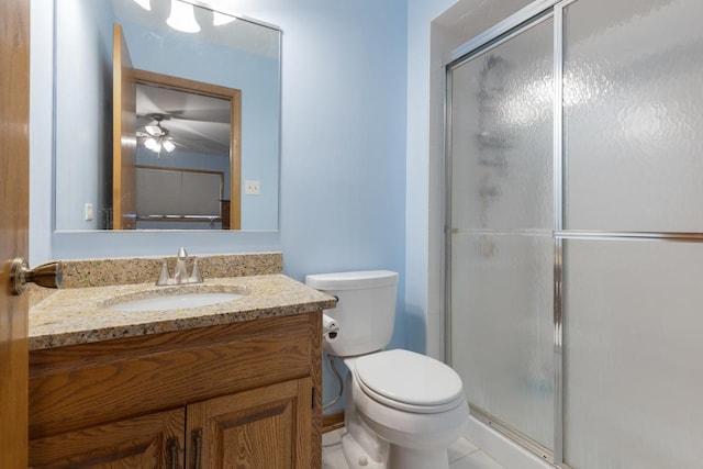 bathroom featuring vanity, a shower with door, ceiling fan, tile patterned flooring, and toilet