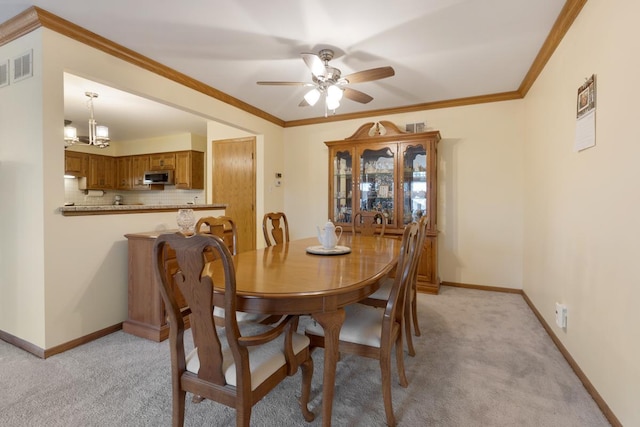 dining space featuring ceiling fan with notable chandelier, ornamental molding, and light carpet