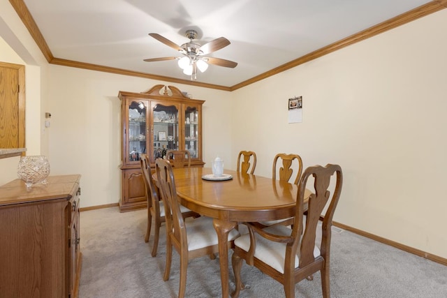 dining room with ceiling fan, light colored carpet, and ornamental molding