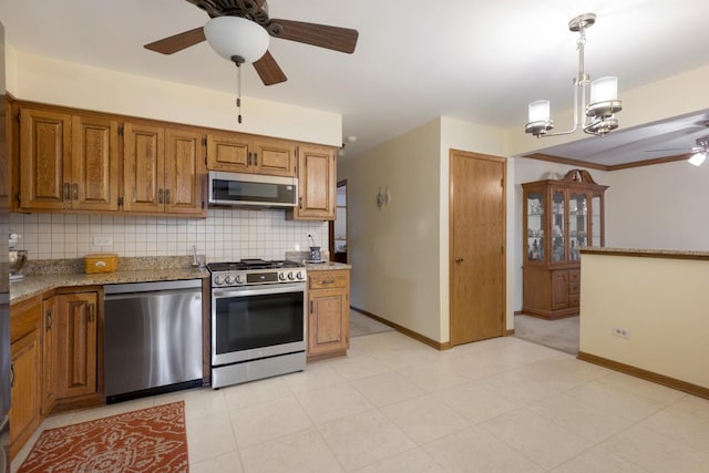 kitchen with decorative backsplash, ceiling fan with notable chandelier, stainless steel appliances, and decorative light fixtures