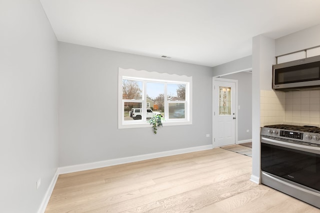 kitchen with light wood-type flooring, appliances with stainless steel finishes, and tasteful backsplash