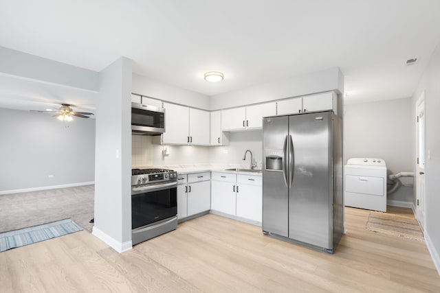 kitchen featuring stainless steel appliances, white cabinetry, washer / clothes dryer, and light hardwood / wood-style flooring