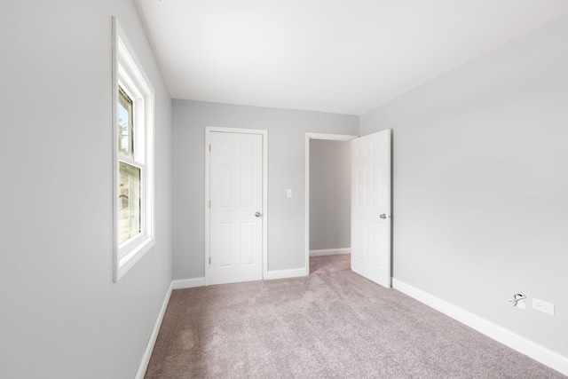 unfurnished bedroom with light carpet and multiple windows