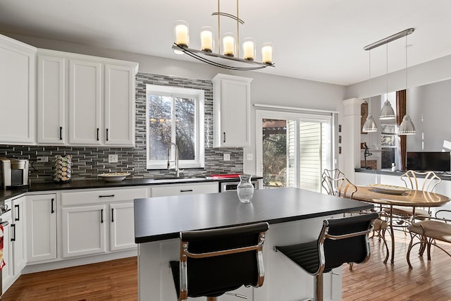 kitchen featuring sink, white cabinets, pendant lighting, and decorative backsplash