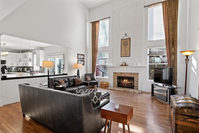 living room with a fireplace, hardwood / wood-style flooring, a high ceiling, and a healthy amount of sunlight