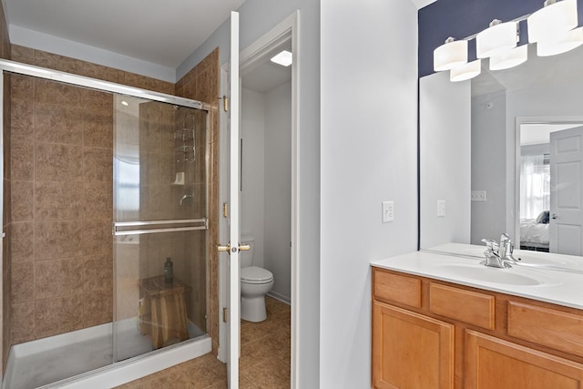 bathroom with toilet, tile patterned flooring, a shower with shower door, and vanity