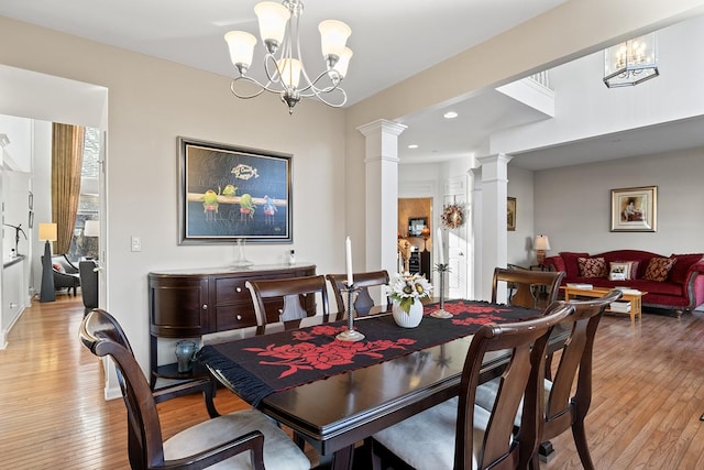 dining space featuring light hardwood / wood-style flooring, ornate columns, and an inviting chandelier