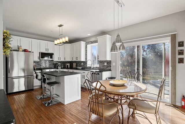 kitchen featuring white cabinetry, appliances with stainless steel finishes, hanging light fixtures, and a kitchen island