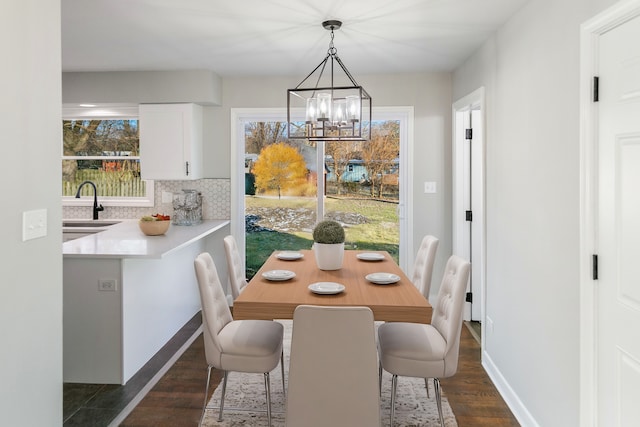 dining area with sink, dark hardwood / wood-style floors, and an inviting chandelier