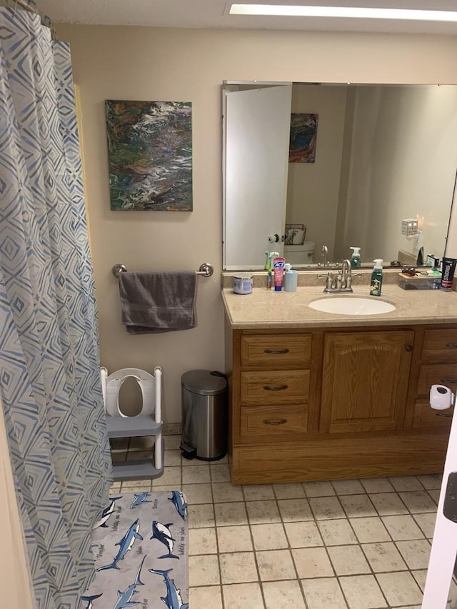 bathroom with toilet, vanity, and tile patterned floors