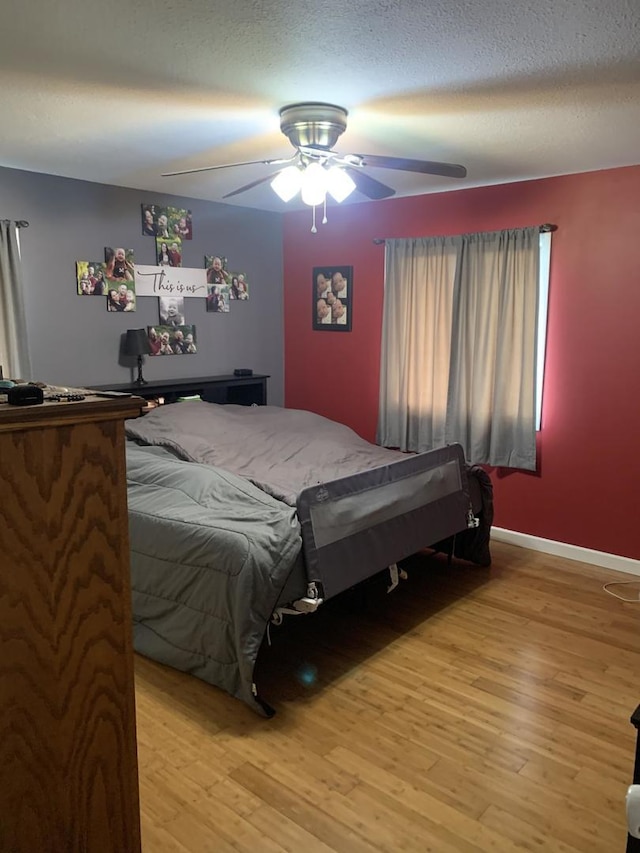 bedroom with ceiling fan, light wood-type flooring, and a textured ceiling