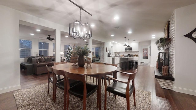 dining area featuring ceiling fan with notable chandelier and dark wood-type flooring