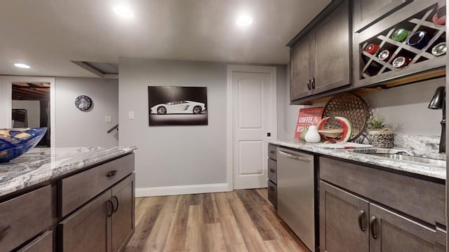 kitchen with sink, light hardwood / wood-style flooring, stainless steel dishwasher, light stone counters, and dark brown cabinetry