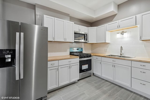 kitchen featuring white cabinetry, stainless steel appliances, and wood counters