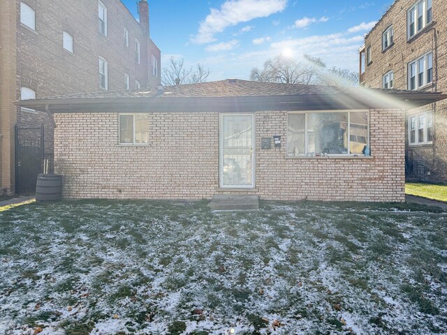 snow covered rear of property featuring a yard