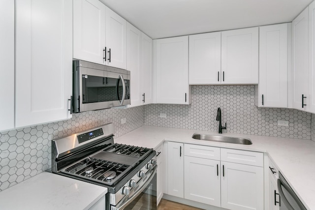 kitchen with decorative backsplash, sink, white cabinets, and stainless steel appliances