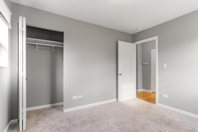 unfurnished bedroom featuring light colored carpet and a closet