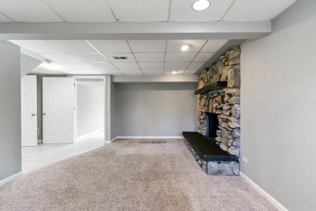 basement with a paneled ceiling, light colored carpet, and a fireplace