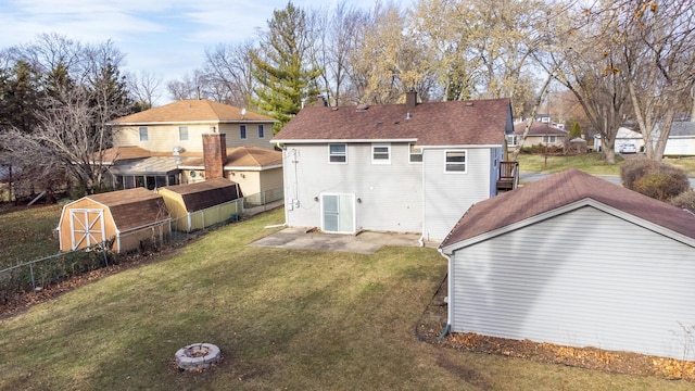 rear view of house featuring a lawn and a storage unit