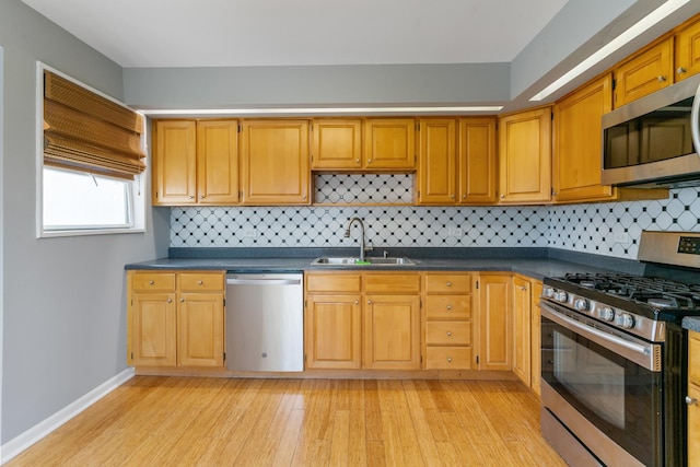 kitchen with light wood-type flooring, sink, appliances with stainless steel finishes, and tasteful backsplash