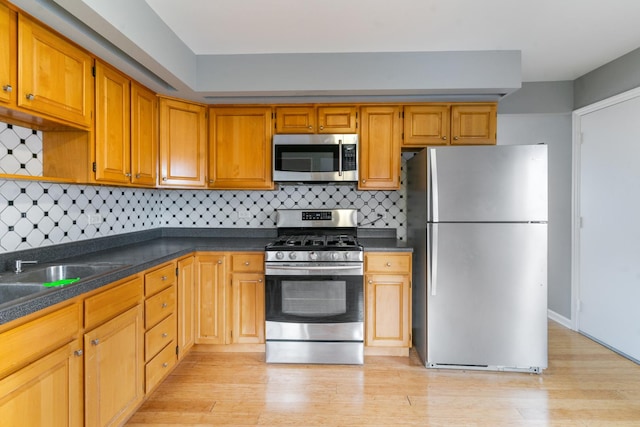 kitchen with tasteful backsplash, stainless steel appliances, and light hardwood / wood-style floors