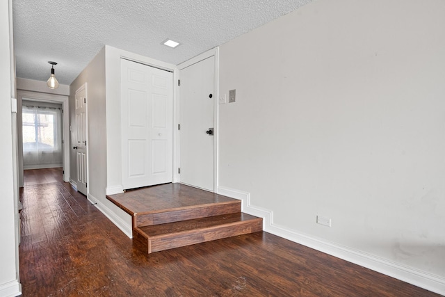 hallway featuring dark wood-type flooring and a textured ceiling