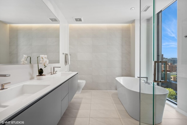 bathroom featuring tile patterned flooring, a wealth of natural light, tile walls, and a bathing tub