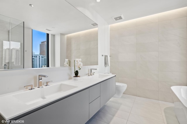 bathroom featuring toilet, vanity, tile patterned floors, and tile walls