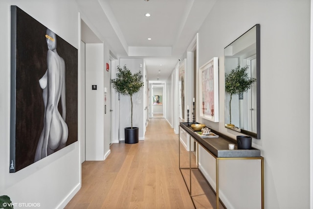 corridor featuring elevator and light hardwood / wood-style flooring