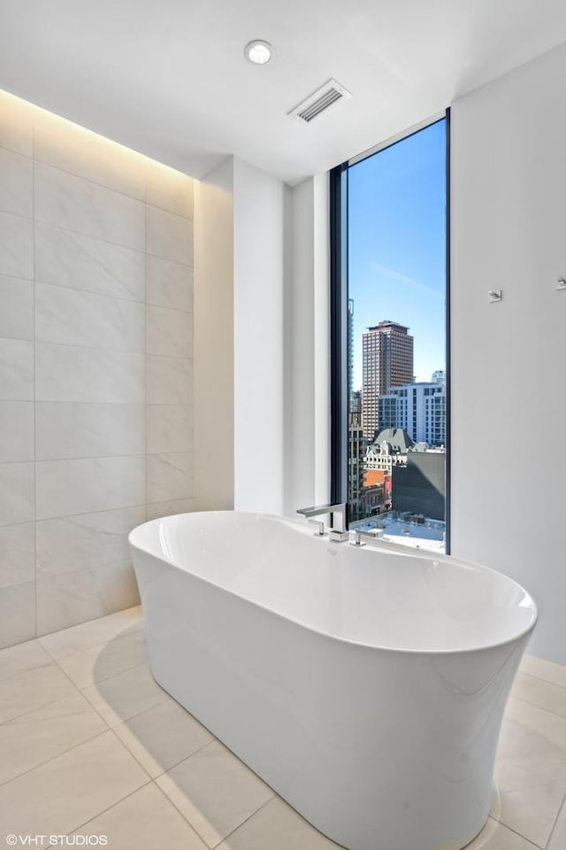 bathroom with tile patterned flooring, a wall of windows, and a tub