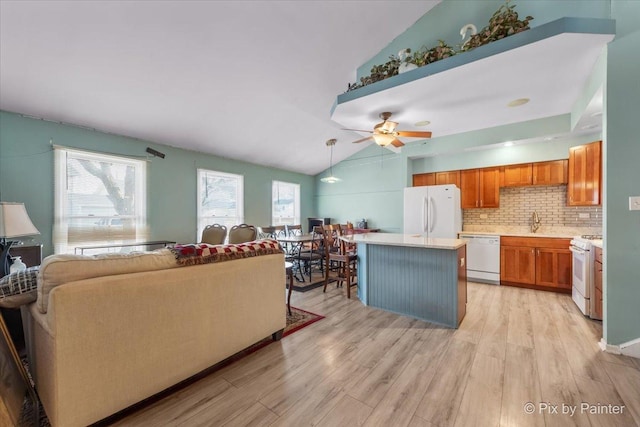 living room with light hardwood / wood-style flooring, plenty of natural light, lofted ceiling, and sink