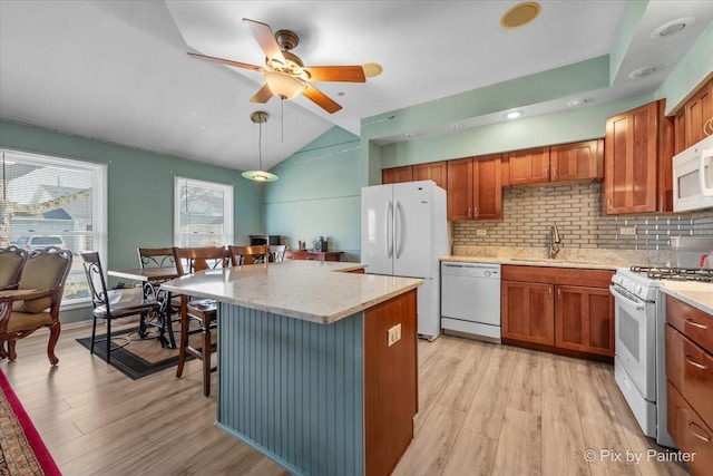 kitchen with light wood-type flooring, white appliances, sink, pendant lighting, and a kitchen island