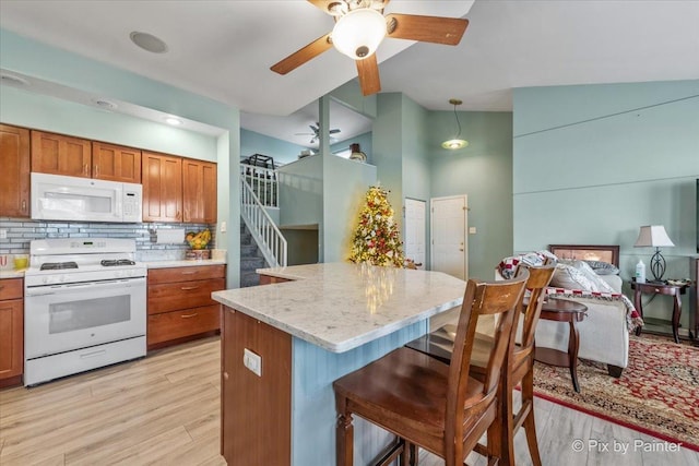 kitchen featuring a center island, pendant lighting, white appliances, decorative backsplash, and light wood-type flooring