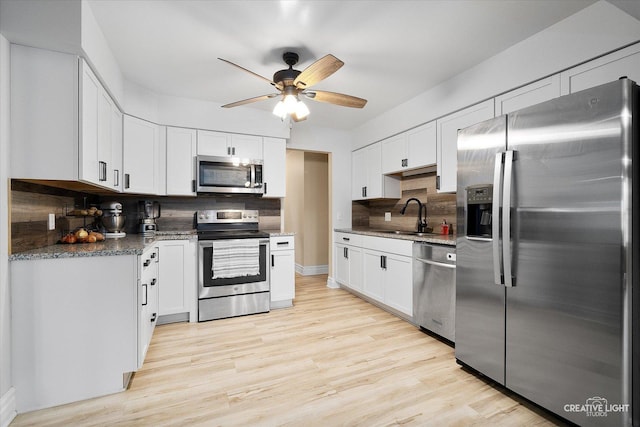 kitchen featuring sink, backsplash, white cabinets, and appliances with stainless steel finishes