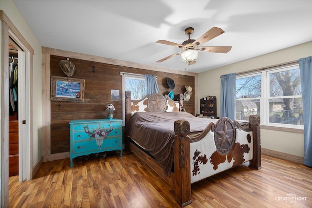 bedroom featuring ceiling fan, hardwood / wood-style floors, and wood walls