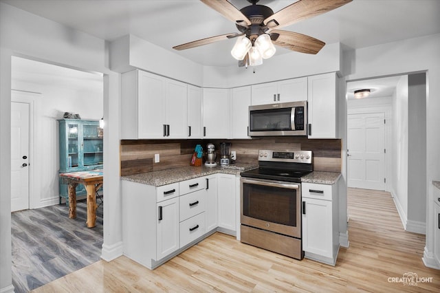 kitchen featuring appliances with stainless steel finishes, backsplash, white cabinets, light stone counters, and light hardwood / wood-style floors