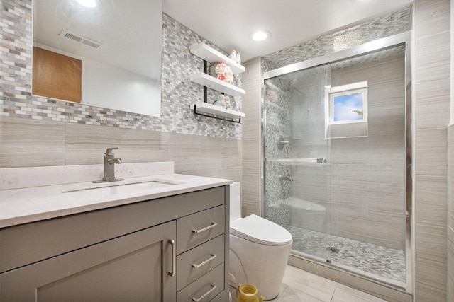 bathroom with vanity, tile walls, tile patterned flooring, toilet, and a shower with shower door